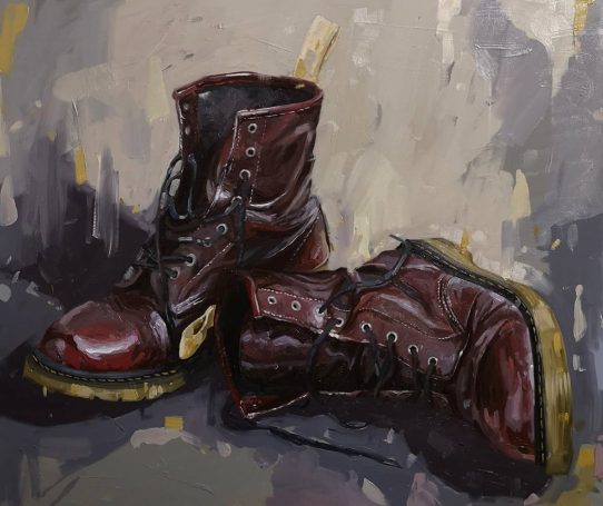 Pair of worn, polished burgundy leather boots with black soles.