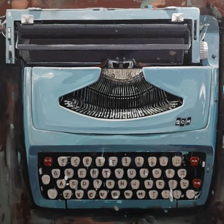 Vintage blue typewriter with black paper feed and white keys on a wooden surface.