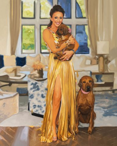 M R with dogs Oil painting commissioned of a Woman in a golden dress holds a puppy, with a dog seated beside her in a stylish living room.
